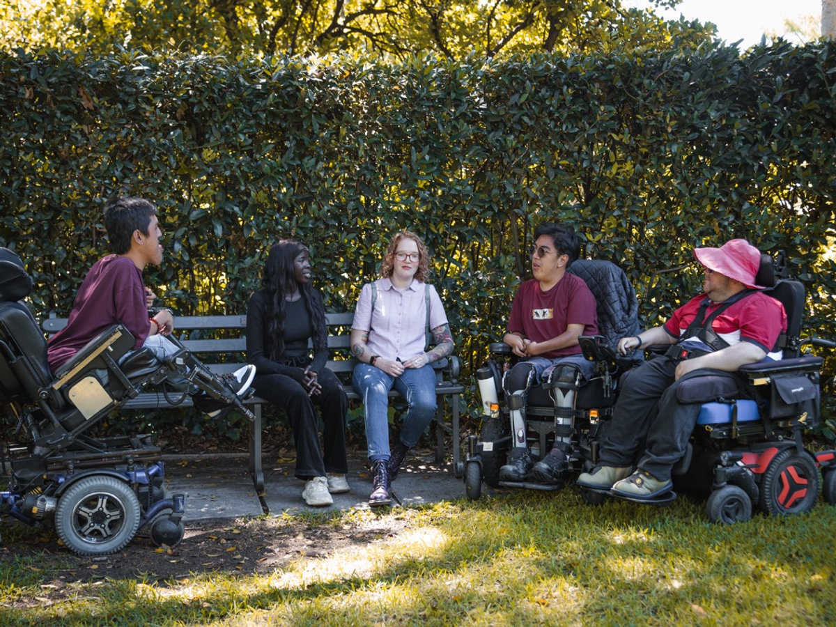 A group of Support Your Way participants and support workers chatting together in a park